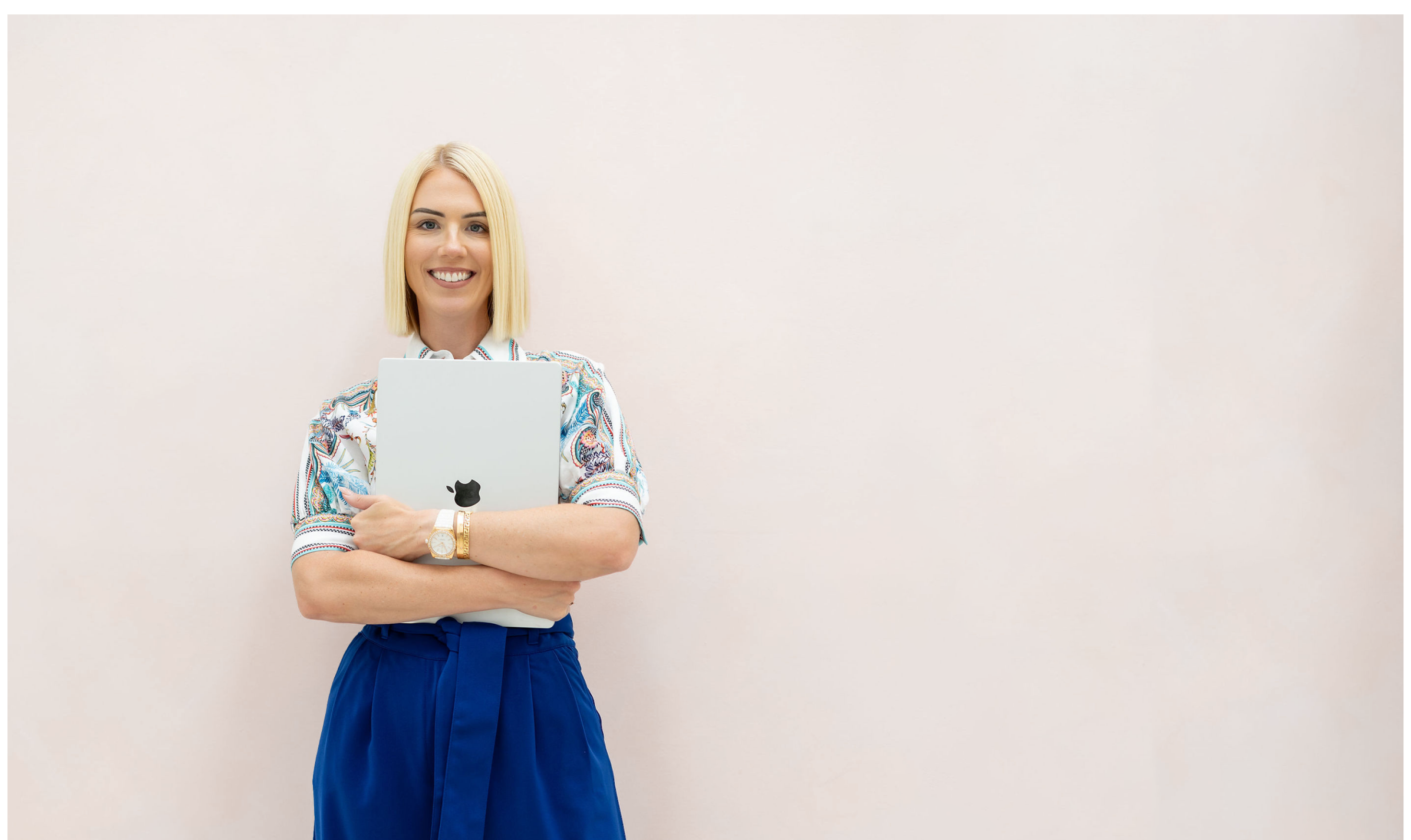 Jessica Gwynne standing with a laptop in a cream studio.